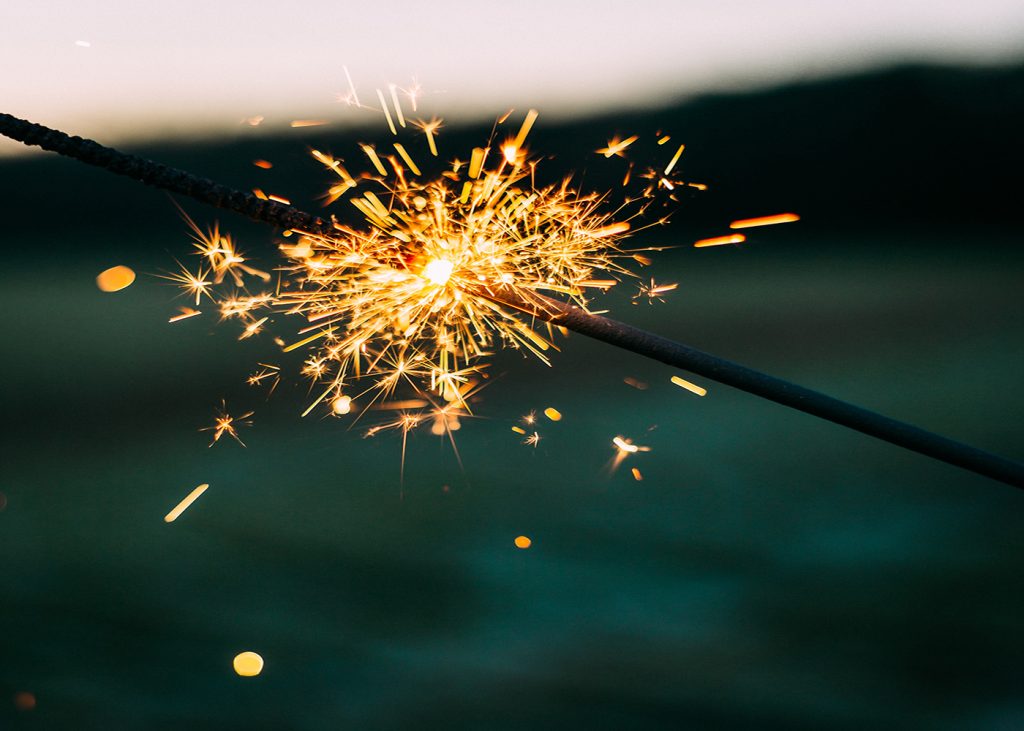 A single sparkler burning brightly against a dark evening backdrop, representing celebration and joy.