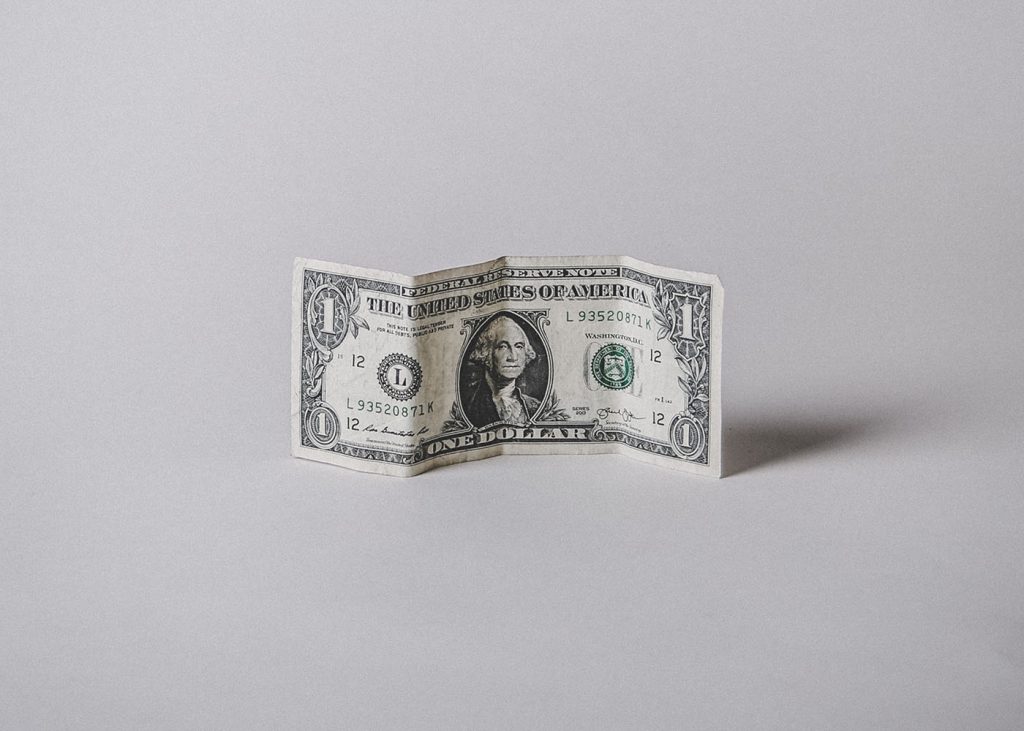 An image of a folded 1 USD dollar bill resting on a plain white surface.
