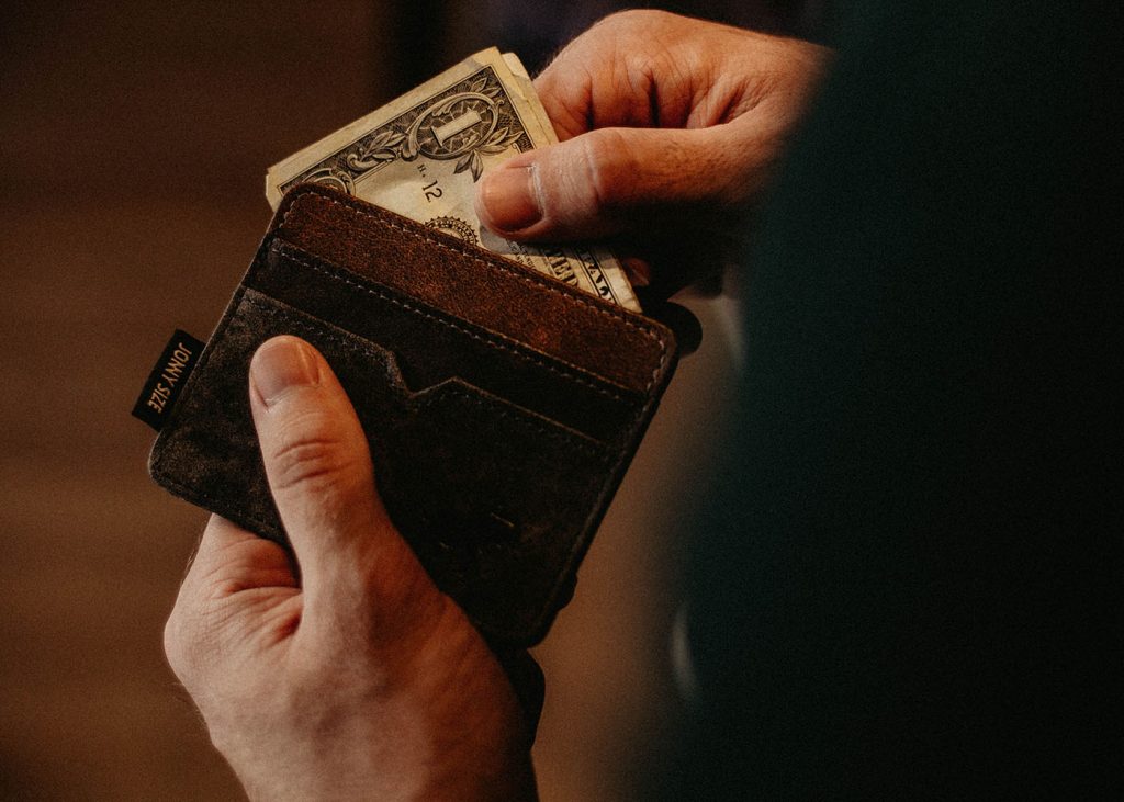 An individual displaying a wallet containing cash.
