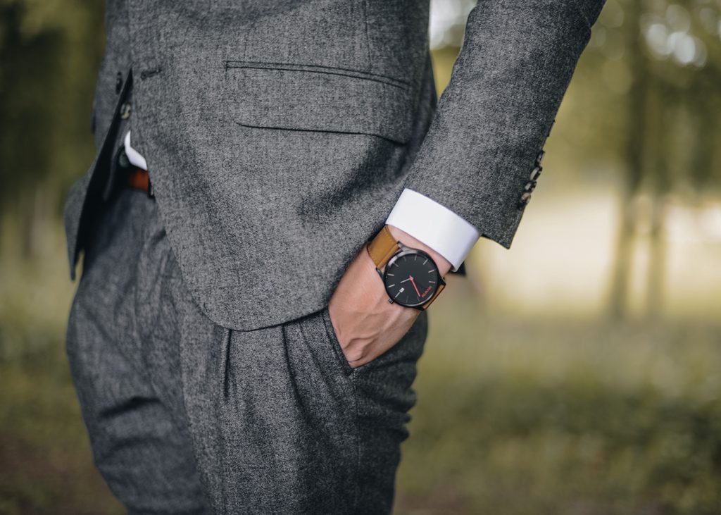 A well-dressed man holding his watch, exuding professionalism and sophistication.