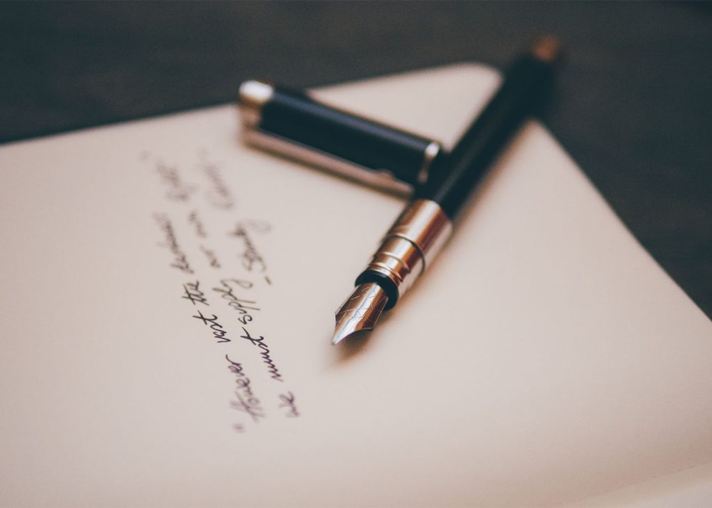 A fountain pen resting on a handwritten note, showcasing the elegance of traditional communication.